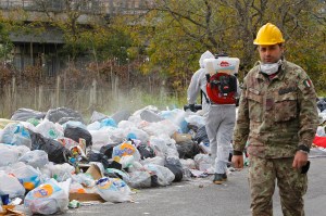 Italian soldier walks past a pile of garbage in Quarto near Naples