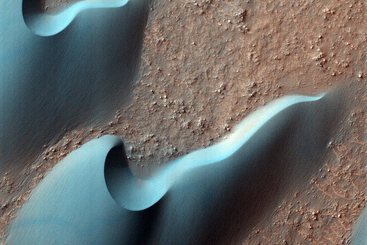 Most of the dunes visible in this observation are barchan dunes. On barchan dunes, the steep slip face is between two "horns" that point downwind.
