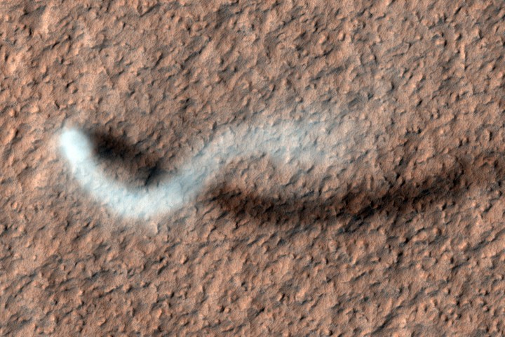 A towering dust devil casts a serpentine shadow over the Martian surface in this stunning, late springtime image of Amazonis Planitia. The length of the shadow indicates that the dust plume reaches more than 800 meters, or half a mile, in height. Mars's thin atmosphere—less than 1% of Earth's—can still whip up considerable winds.
