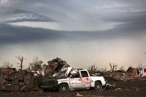 A mangled car rest amongst leveled homes and stripped trees the day after a killer tornado hit in Moore, Okla., May 21 , 2013.