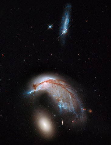 Interacting galaxy duo Arp 142 captured by NASA Hubble Space Telescope, released on June 21, 2013. The pair contains the disturbed, star-forming spiral galaxy NGC 2936, along with its elliptical companion, NGC 2937 at lower left.