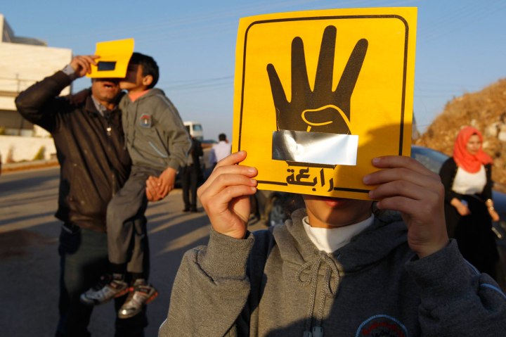 People shield their faces with specially-constructed cards showing the four-finger symbol of Rabaa to show their support for ousted Egyptian President Mohamed Mursi as they observe a solar eclipse in Amman, on Nov. 3, 2013.