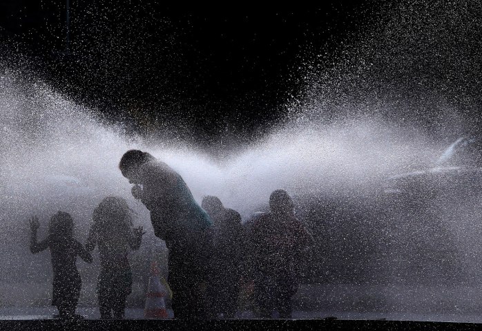 People cool off in the spray of an open hydrant on a hot evening in Lawrence, Mass., July 16, 2013.